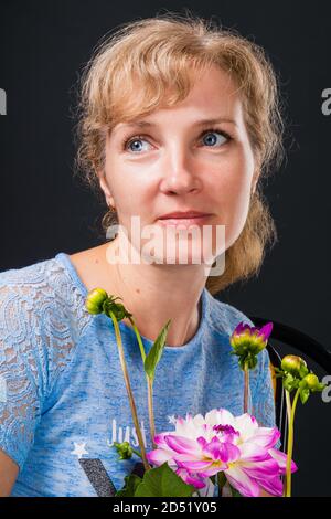 Femme pensive tendre de 45 ans avec des fleurs Banque D'Images