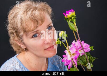 Femme pensive tendre de 45 ans avec des fleurs Banque D'Images