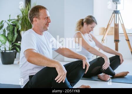 Groupe de jeunes s'amuser pendant la pratique en cours de yoga Banque D'Images