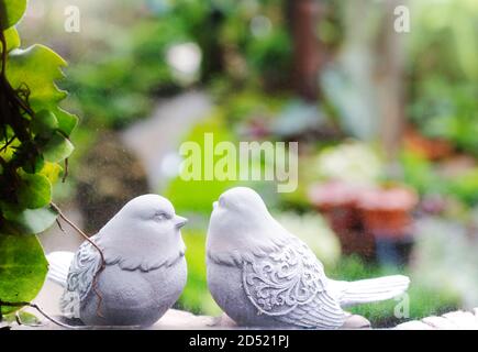 Couple d'oiseaux, deux statues d'oiseaux blancs dans le jardin à travers la fenêtre Banque D'Images