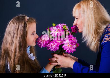 Petite fille donne des fleurs à maman et lui souhaite avec les mères jour Banque D'Images