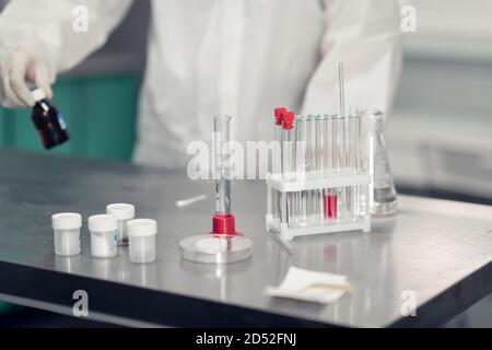 Un scientifique travaillant dans un laboratoire chimique. Équipement de laboratoire et verrerie contenant des liquides chimiques au premier plan. Banque D'Images