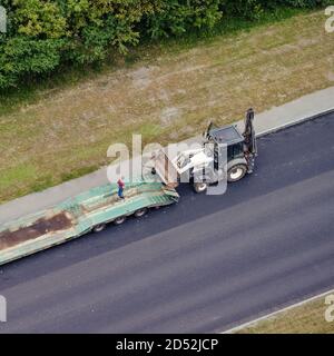 Les travailleurs chargent l'équipement de construction sur une remorque de camion pour le transport vers un autre emplacement Banque D'Images