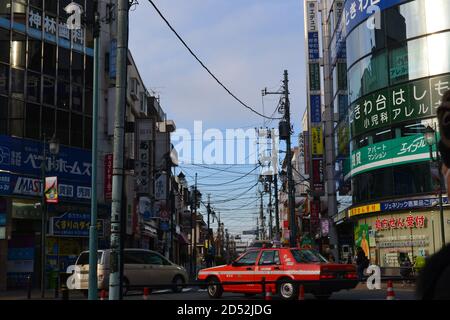 Tokyo, Japon-2/24/16: Deux voitures tournant en même temps dans une rue de Tokyo; le taxi (rouge) heurte leurs freins pendant que le minibus descend. Banque D'Images