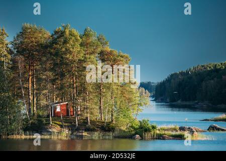 Suède. Magnifique cabane en bois rouge suédois sur la côte des îles Rocheuses en été Sunny soir. Paysage de lac ou de rivière Banque D'Images