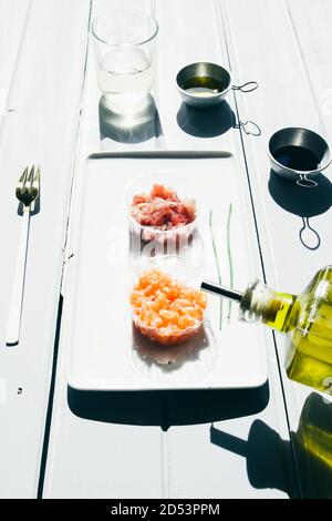 Poisson tartare, saumon et thon sur un plat blanc rectangulaire sur une table en bois .lumière naturelle , vue frontale sur un tableau blanc. Banque D'Images