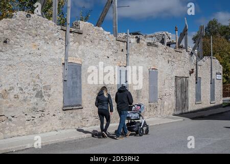 Un jeune couple avec leur enfant dans la poussette se promenant le long du mur de l'ancienne chapelle à Elora, en Ontario. Banque D'Images