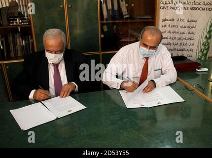 Gaza. 12 octobre 2020. Abdul Latif al-Haj (R), directeur des affaires hospitalières au ministère de la Santé de Gaza, et Maamoun Abu Shahla, président de l'association caritative Gun Palestine, signent un accord à Gaza, le 12 octobre 2020. Un organisme de bienfaisance palestinien a signé lundi un accord avec le ministère de la Santé de Gaza pour fournir et installer des panneaux d'énergie solaire financés par la Chine pour un hôpital pour enfants dans la ville de Gaza. Credit: Rizek Abdeljawad/Xinhua/Alamy Live News Banque D'Images