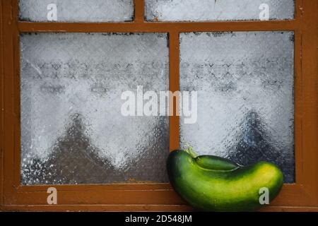 Courgette verte sur fenêtre marron Banque D'Images