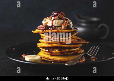 Crêpes savoureuses à la citrouille avec banane, noix et caramel servies dans un plat. Gros plan Banque D'Images