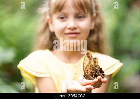 jolie petite fille tenant vivant beau papillon sur sa main Banque D'Images