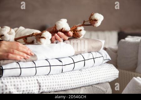 Les mains de la femme bien entretenues tiennent la branche de coton avec la pile de draps pliés et de couvertures Banque D'Images