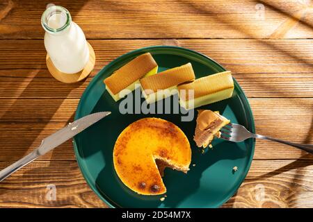 manger un morceau de gâteau au fromage avec des gâteaux au matcha et une bouteille de lait à l'arrière-plan dans une composition horizontale matinale ensoleillée Banque D'Images