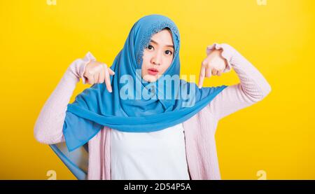 Asiatique musulman arabe, Portrait de la bonne belle jeune femme Islam religieux porter voile hijab sourire drôle elle l'expression positive points doigt vers le bas avec Banque D'Images