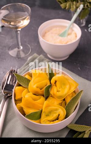 Tortelloni avec feuilles de sauge, ricotta et épinards. Pâtes italiennes et vin blanc. Cuisine traditionnelle de Bologne, région de l'Émilie-Romagne. Photo de haute qualité. Copier l'espace Banque D'Images