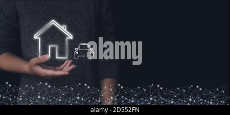 La main de femme tient un hologramme virtuel à la maison et en voiture. Concept de vie familiale et d'affaires immobilières Banque D'Images