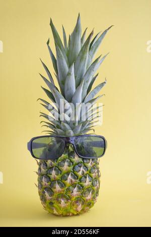 Ananas mûr avec lunettes de soleil sur fond jaune Banque D'Images