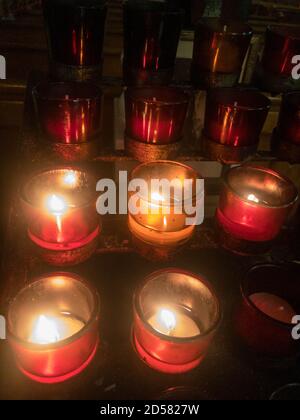 Les bougies votives rouges scintillent dans une église catholique. Banque D'Images