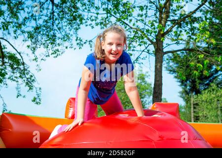 Happy little girl ayant beaucoup de plaisir lors d'un saut de balle à balle sur un château gonflable. Banque D'Images