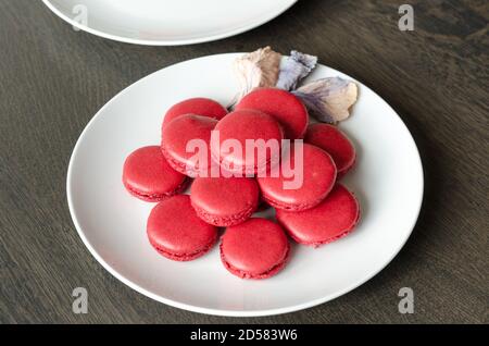 Macarons rouges aux baies maison dans une assiette blanche, servi comme dessert pour le café à la maison. Maison plaisir pâtisserie, quarantaine idées Banque D'Images