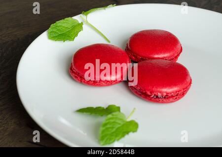 Macarons rouges aux baies maison dans une assiette blanche, servi comme dessert pour le café à la maison. Maison plaisir pâtisserie, quarantaine idées Banque D'Images