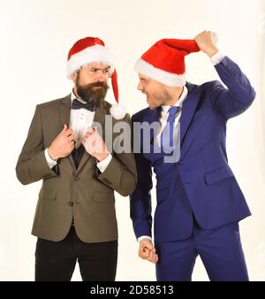 Collègues avec des barbes argumenter sur les affaires. Célébration de Noël au travail concept. Les hommes en costumes et smart Santa hats isolé sur fond blanc. Les hommes d'affaires avec crazy visages crier à l'autre. Banque D'Images