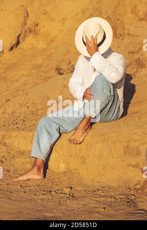 guy en jean léger chapeau blanc et chemise au lever du soleil Banque D'Images