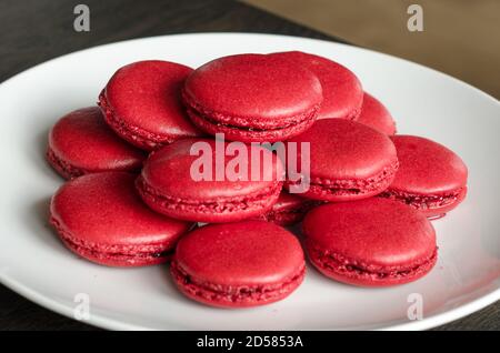 Macarons rouges aux baies maison dans une assiette blanche, servi comme dessert pour le café à la maison. Maison plaisir pâtisserie, quarantaine idées Banque D'Images