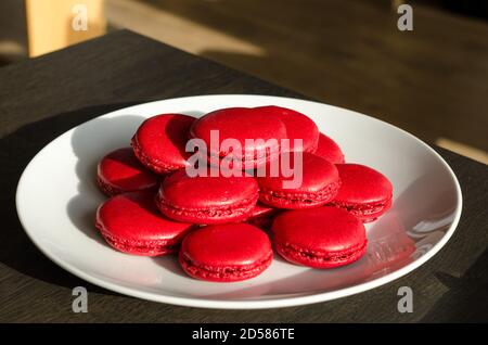 Macarons rouges aux baies maison dans une assiette blanche, servi comme dessert pour le café à la maison. Maison plaisir pâtisserie, quarantaine idées Banque D'Images