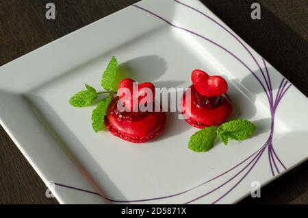 Macarons rouges aux baies maison dans une assiette blanche, servi comme dessert pour le café à la maison. Maison plaisir pâtisserie, quarantaine idées Banque D'Images