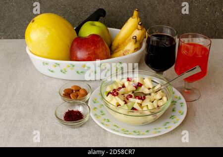 Plat de fruits à la poire, à la pomme rouge, à la pomme verte, à la banane et au Canary Melon dans une assiette. Bol contenant une salade de fruits, un bol d'amande et de safran. Glas Banque D'Images