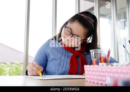 Fille avec le syndrome de Down dessin image avec crayon dans la classe d'art. Concept d'apprentissage des enfants handicapés. Banque D'Images