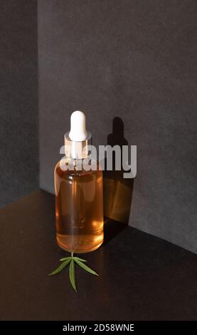 Bouteilles en verre et compte-gouttes D'HUILE CBD, teinture de THC et feuilles de cannabis sur fond noir. Production en laboratoire de cosmétiques avec de l'huile CBD. Banque D'Images