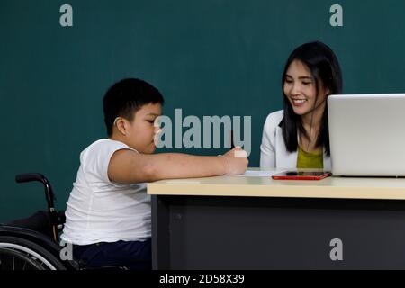 Enfant asiatique handicapé en fauteuil roulant avec un enseignant en classe. Banque D'Images