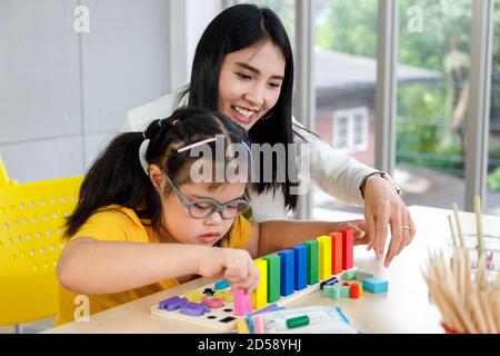 Asiatique fille avec le syndrome de Down jouer jouet puzzle avec son professeur en classe. Banque D'Images