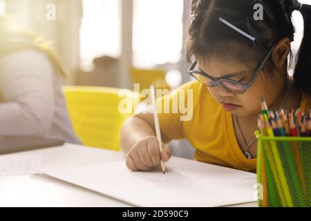 Fille asiatique avec le syndrome de Down dessin image dans la classe d'art. Concept d'apprentissage des enfants handicapés. Banque D'Images