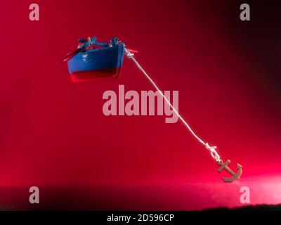 Bateau à ramer conceptuel flottant à mi-vol tout en déposant l'ancre Banque D'Images