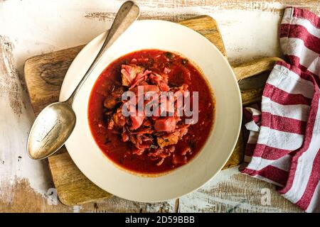 Vue en hauteur d'un bol de soupe de betteraves ukrainiennes une planche à découper en bois Banque D'Images