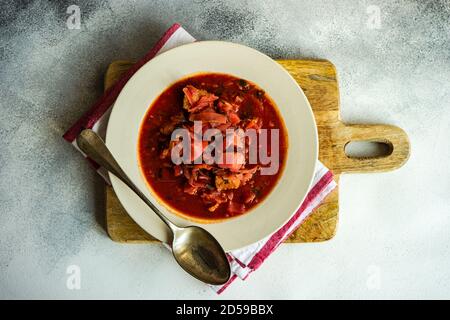 Vue en hauteur d'un bol de soupe de betteraves ukrainiennes une planche à découper en bois Banque D'Images