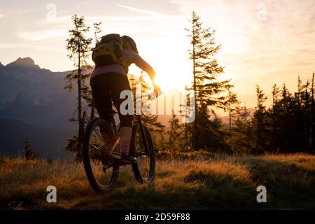 Vue arrière d'une femme VTT en montagne au lever du soleil, Fadstadt, Salzbourg, Autriche Banque D'Images