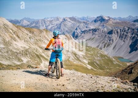 Vue arrière d'une femme sur un vélo tout-terrain, vue sur la montagne, Arosa, vallée de Schanfigg, Graubunden, Suisse Banque D'Images