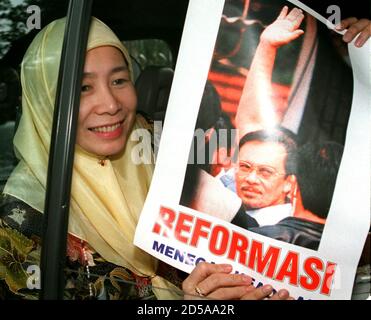 Wan Azizah Wan Ismail, wife of sacked Malaysian finance minister Anwar Ibrahim, smile as she shows a poster of Anwar while leaving the Malaysian High Court in Kuala Lumpur December 9. Anwar, who was sacked and arrested in September, has pleaded not guilty to five counts each of corruption and sodomy.