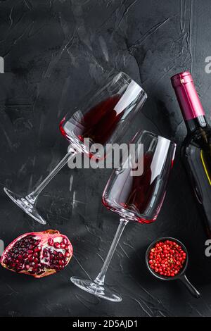 Deux verres de vin rouge avec bouteille sur fond noir texturé, vue du dessus. Banque D'Images