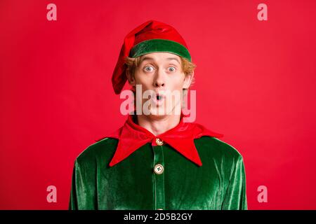 Portrait de l'orf étonnant gars regarder dans l'appareil photo incroyable nouvelles écoutez porter un chapeau de costume vert isolé sur fond rouge Banque D'Images