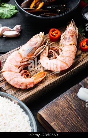 Très grandes crevettes avec ingrédients sur une table en bois noir Banque D'Images