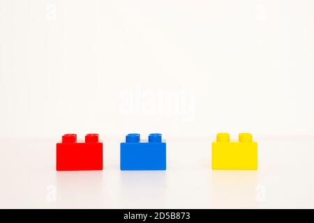 Rangée de trois blocs de construction rouge, jaune et bleu. Isolé. Arrière-plan blanc avec espace de copie. Banque D'Images