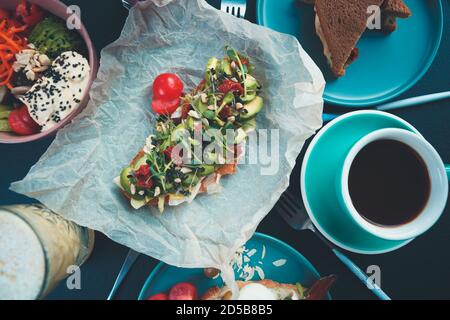 Petit déjeuner végétarien sain dans un plat Lay.avocat toast avec avocat frais, dryed tomates cerises, microverts servis sur l'assiette avec sandwichs, tasse de café Banque D'Images