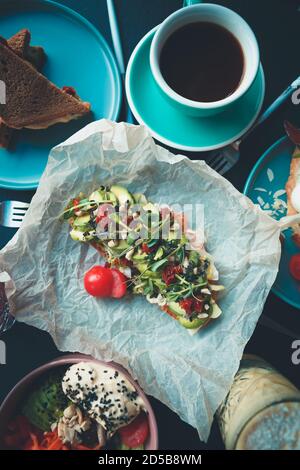 Petit déjeuner végétarien sain servi sur table dans le café vegan.délicieux avocat toast préparé avec des tranches d'avocats, des tomates séchées, des légumes verts sur le brusch Banque D'Images