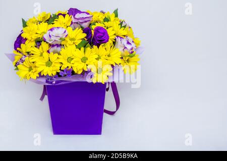 Magnifique bouquet coloré lumineux avec chrysanthème jaune et eustoma pourpre fleurs dans une boîte sur fond blanc Banque D'Images