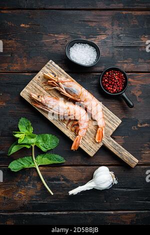 Scampi sur planche à découper sur table sombre en bois, vue de dessus Banque D'Images